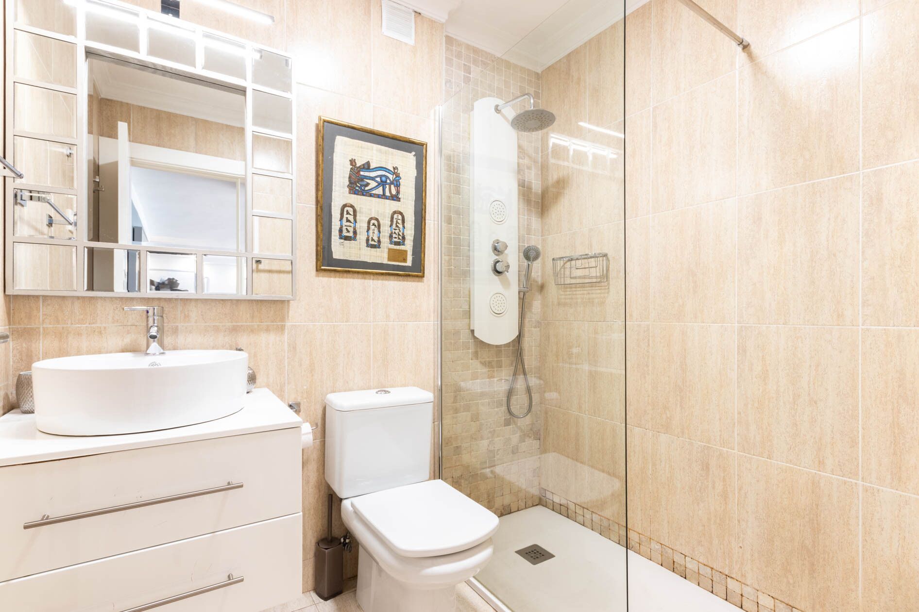 Ein modernes Badezimmer mit einer gläsernen Duschkabine, einem weißen Waschbecken und einer Toilette.