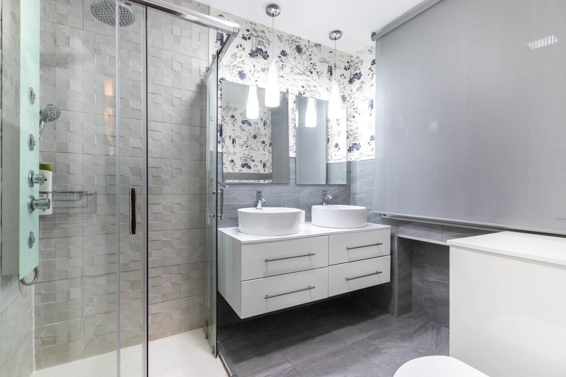 Un baño moderno con cabina de ducha de vidrio, dos lavamanos, un espejo grande y un inodoro.