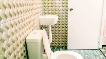 A bathroom with a patterned tile wall, a white toilet, and a sink.