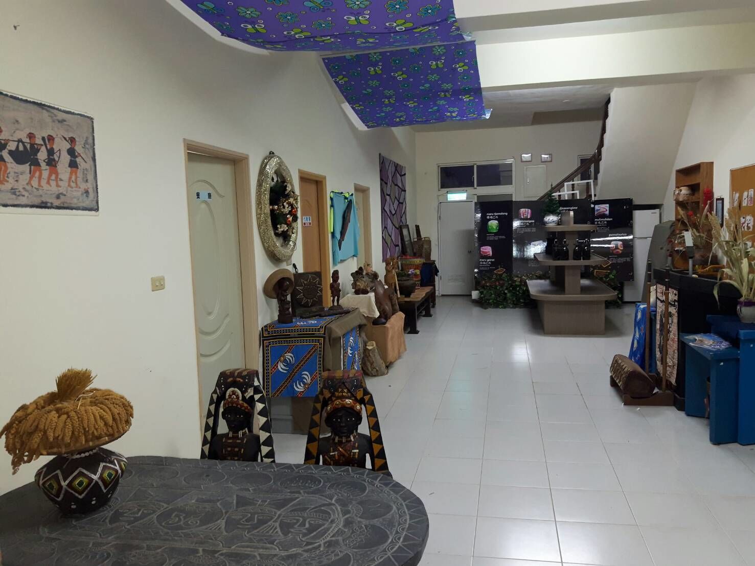 A spacious room with a high ceiling, decorated with various cultural artifacts and furniture.