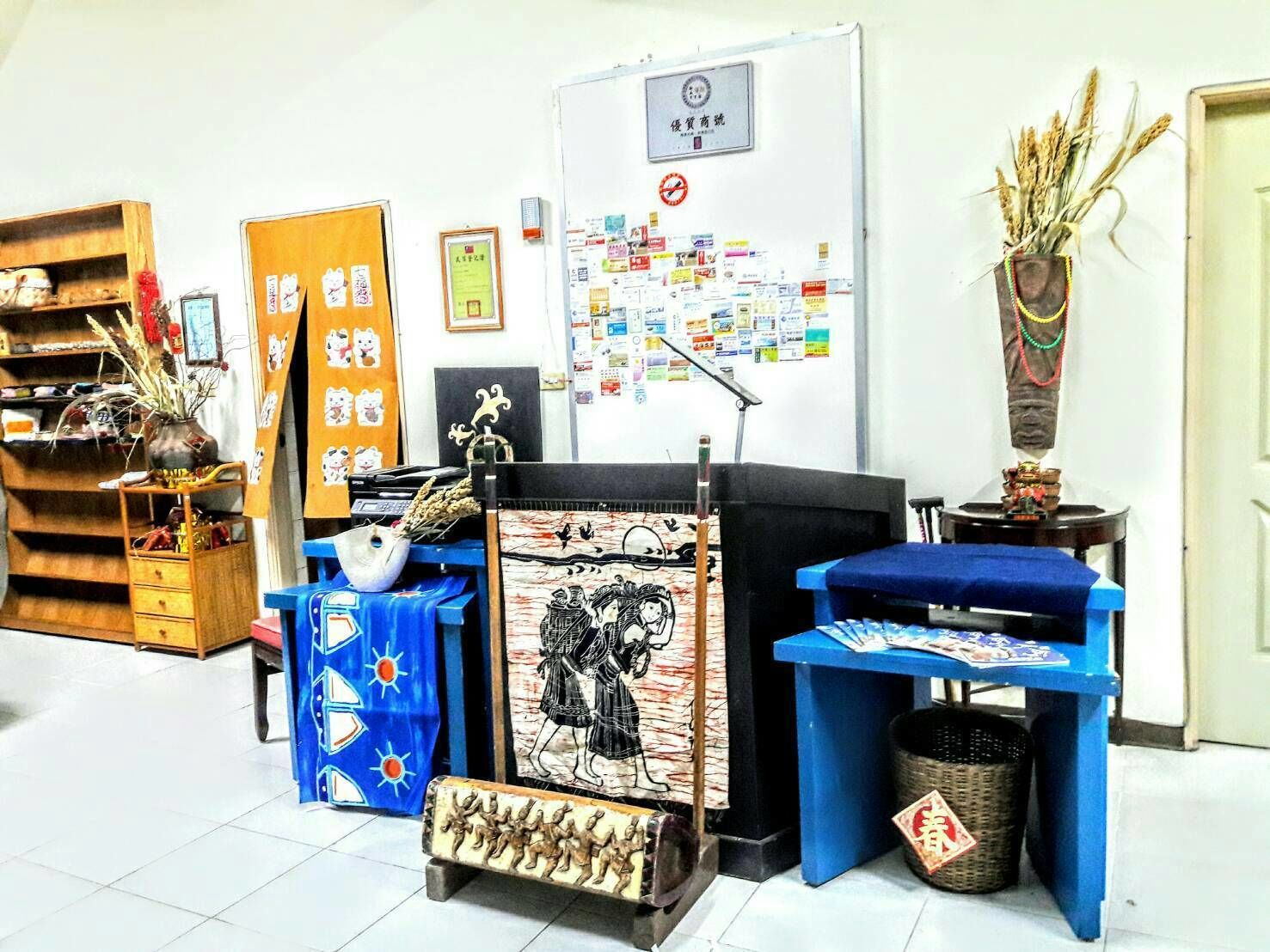 A room with a wooden shelf, a blue table, a bulletin board, and a traditional Chinese painting.