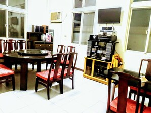 A dining area with a round table and chairs, a television mounted on the wall, and a shelf with various items. - Hsianghua 81 Homestay (Jinsha)