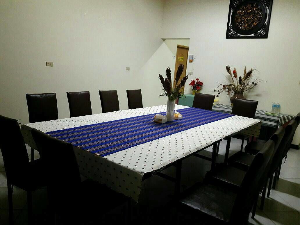 Un comedor con una mesa dispuesta para seis personas, rodeada de sillas. Hay dos jarrones con flores sobre la mesa.