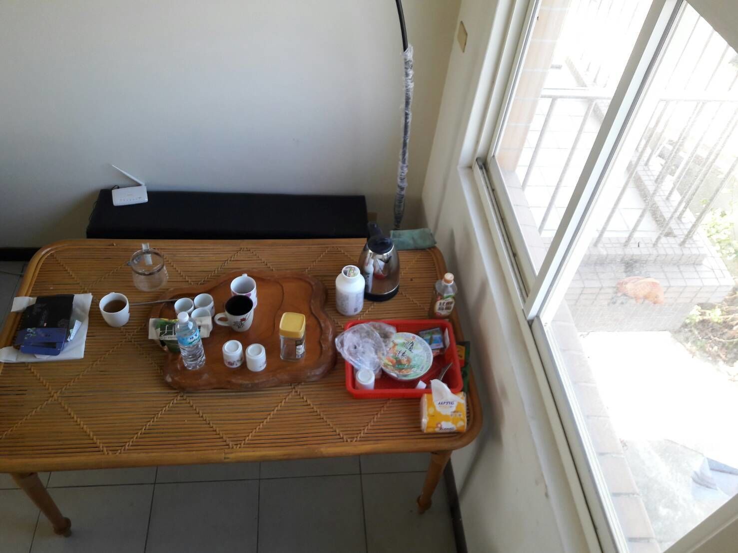 A dining table with various items including cups, a kettle, and a tray with food containers.