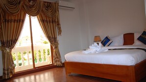 Una habitación de hotel con una cama grande, un balcón con cortinas y un equipo de aire acondicionado.