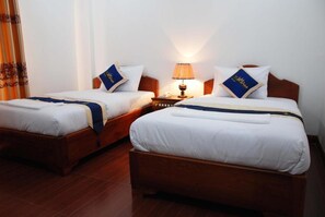 Two single beds with wooden frames, white bedding, and blue decorative pillows. - Emerald BB Battambang Hotel (Battambang)