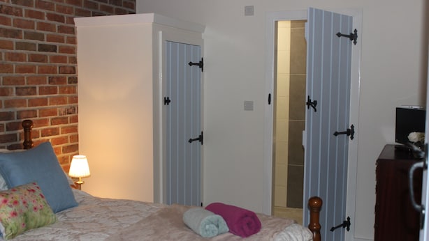 Un dormitorio con cama, almohadas, una lámpara y un armario.