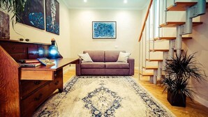 Ein Wohnzimmer mit einer Couch, einem Couchtisch, einem Teppich und einer Treppe.