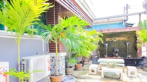 Un patio con plantas en macetas, mobiliario exterior y una pared con el nombre "ARCONRUNG".