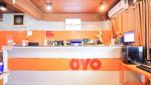 Un mostrador de recepción con el logo "OYO" y un monitor de computadora sobre un atril.