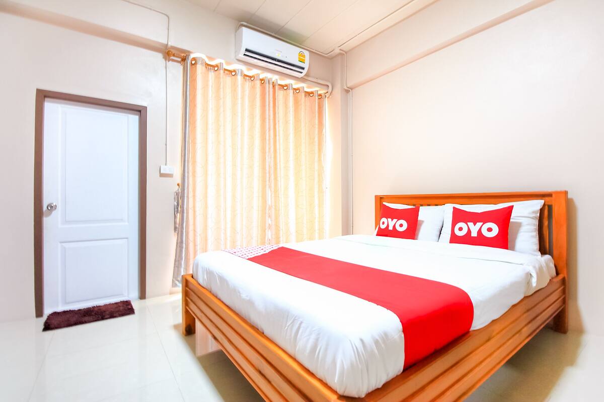 Ein Hotelzimmer mit einem Bett, einer Tür, einer Klimaanlage und einem Vorhang.