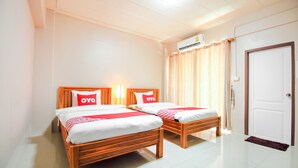 Habitación de hotel con dos camas de madera, ropa de cama blanca y almohadas rojas con la marca 'OYO'.