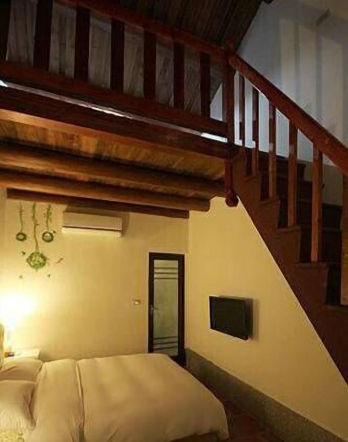 Un dormitorio con cama, una escalera de madera, un televisor instalado en la pared y una puerta.