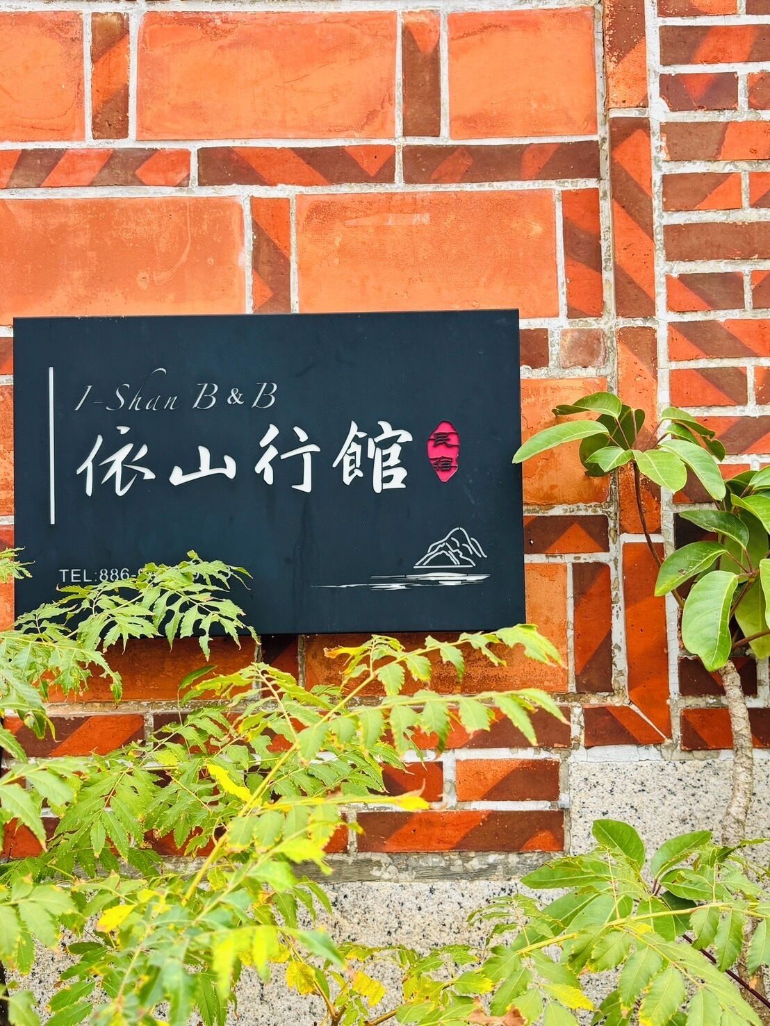 A sign with Chinese characters and a mountain icon, indicating a hotel named 'I-Shan B&B' with a contact number.