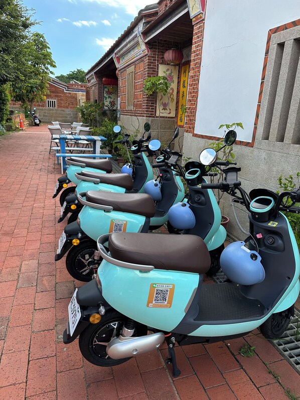 A row of teal scooters parked on a brick pathway. - I-Shan B&B (Jincheng)