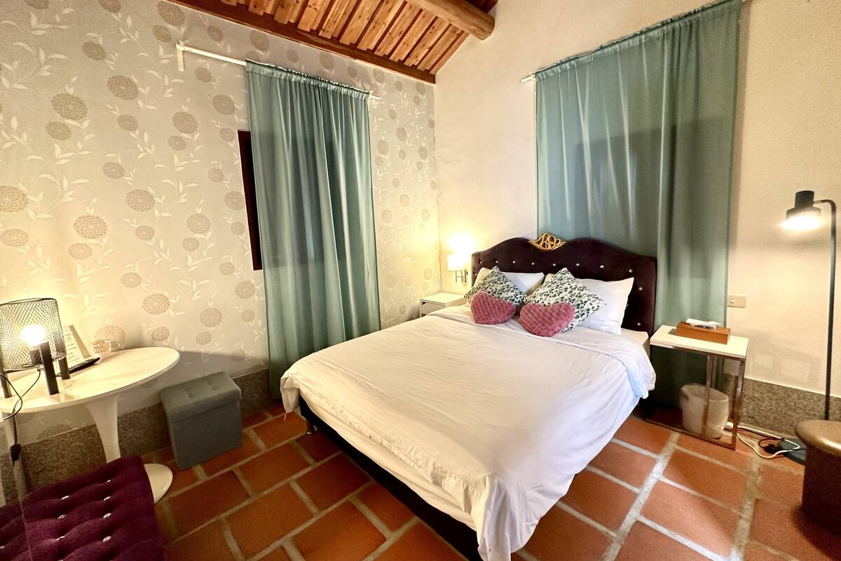 A bedroom with a bed, a nightstand, a lamp, and a chair.