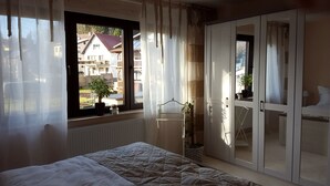 A bedroom with a bed, a window with curtains, a potted plant, and a wardrobe. - Modern comfort apartment in the spa town on the Rennsteig (Friedrichroda OT Finsterbergen)