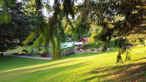 A well-maintained garden with a patio area, a greenhouse, and a small building with a red roof. - Modern comfort apartment in the spa town on the Rennsteig (Friedrichroda OT Finsterbergen)