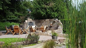 An outdoor patio with stone seating and a fireplace. - Modern comfort apartment in the spa town on the Rennsteig (Friedrichroda OT Finsterbergen)