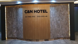 A reception desk with a wooden panel displaying the C&N Hotel name and room numbers. - CNN Hotel (Changwon)