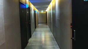 A hallway with multiple doors, each marked with a number and an emergency exit sign. - CNN Hotel (Changwon)