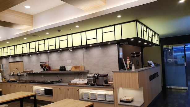 A modern hotel lobby with a reception desk, a coffee station, and a seating area with tables and chairs. - CNN Hotel (Changwon)