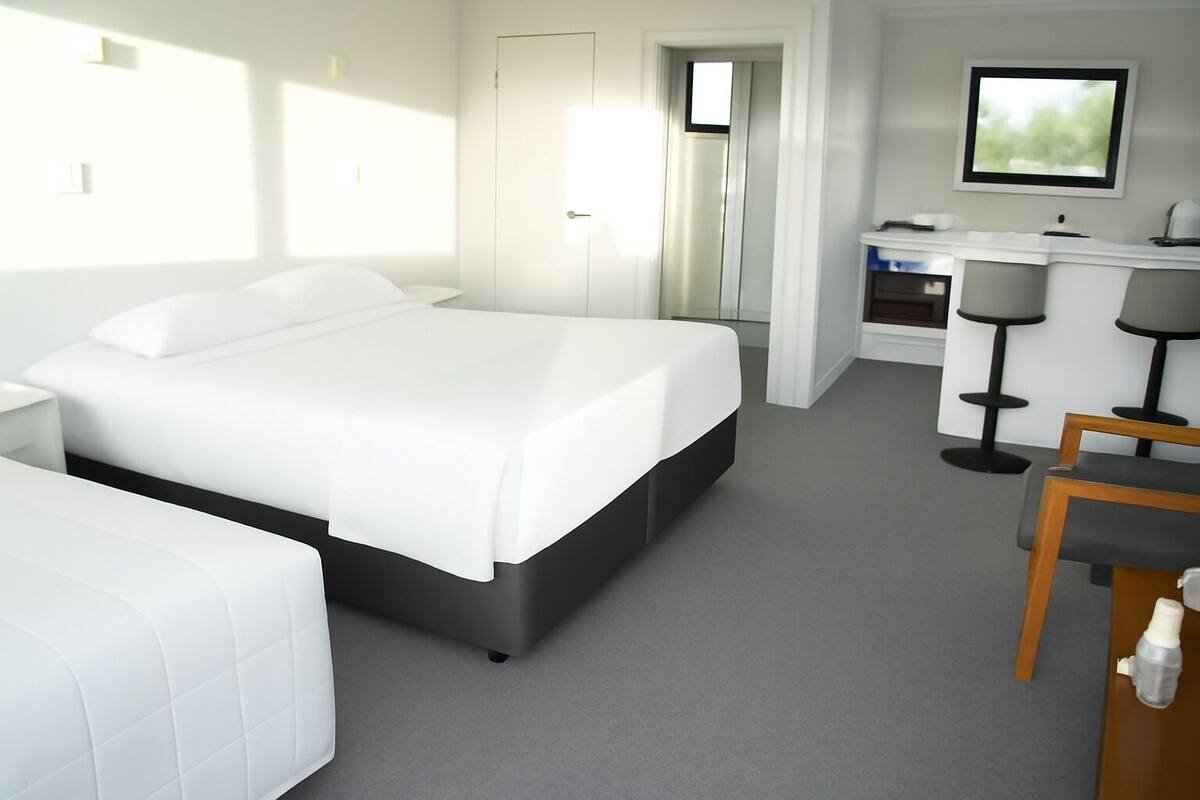 A modern hotel room with a large bed, a desk, and a chair.
