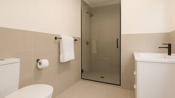 Un baño moderno con inodoro, cabina de ducha de vidrio y lavabo.