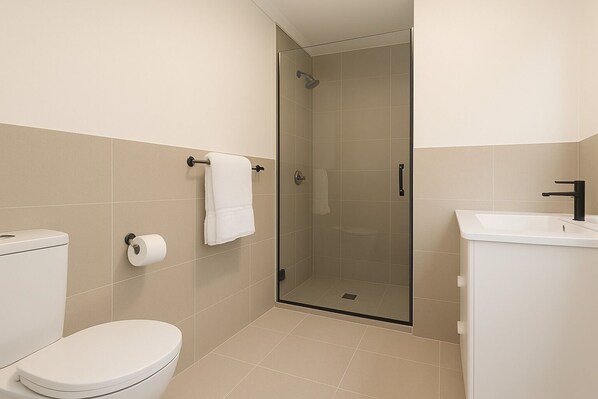A modern bathroom with a toilet, a glass shower enclosure, and a sink.