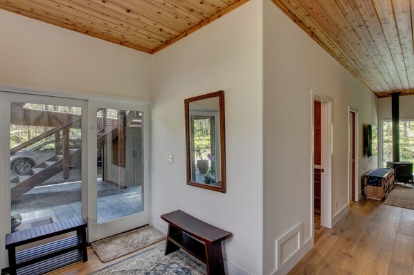 A hallway with wooden flooring, a bench, a mirror, and a door leading to a staircase. - Volcano Forest House next to Volcano National Park (Volcano)