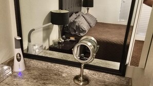 A bathroom with a large mirror, a vanity with a marble countertop, a red bench, and a handheld mirror. - Newer Cavco Home in North Phoenix. Near Glendale, Arrowhead and Peoria (Glendale)