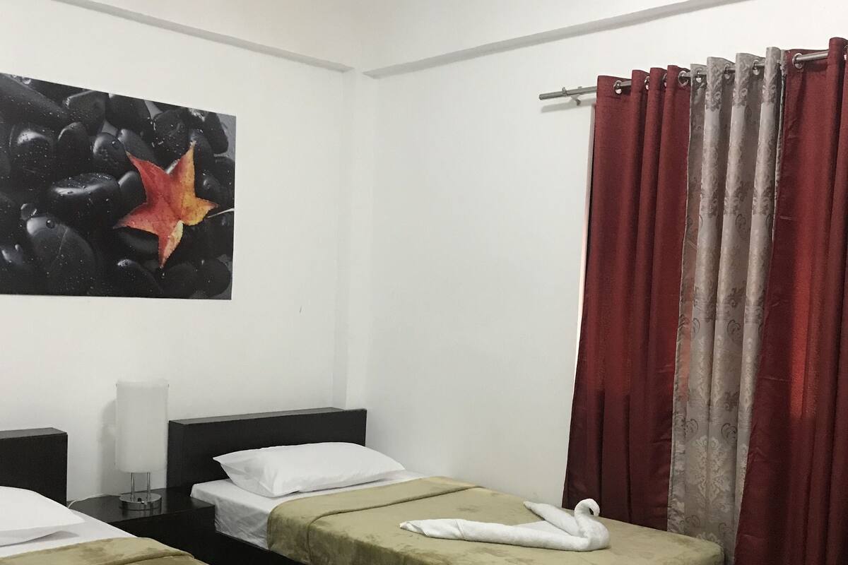 Ein Hotelzimmer mit zwei Betten, einem Gemälde an der Wand und einem roten Vorhang.