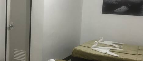 A room with two beds, a door, and a wall-mounted picture.