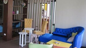 Una sala de estar moderna con un sofá azul, dos sillones, una mesita y una estantería.