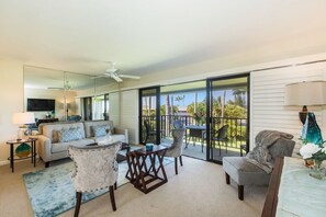 Relax in this stylish living area with a sofa set, coffee table, and dining table, offering a view of the outdoors through large windows.