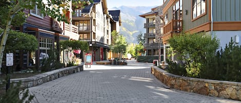 A paved street lined with multi-story buildings, some with balconies, in a mountainous area.
