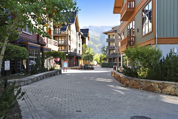 A paved street lined with multi-story buildings, some with balconies, in a mountainous area.