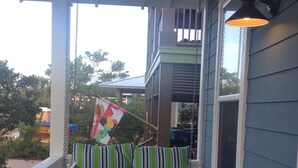A porch with a swing seat and a hanging kite.