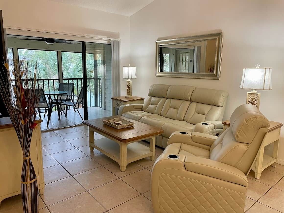 A living room with a beige sofa, a coffee table, and a dining area with chairs and a table.