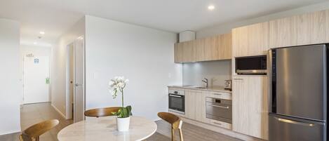 Una cocina moderna con electrodomésticos de acero inoxidable, armarios de madera y una mesa redonda con sillas.