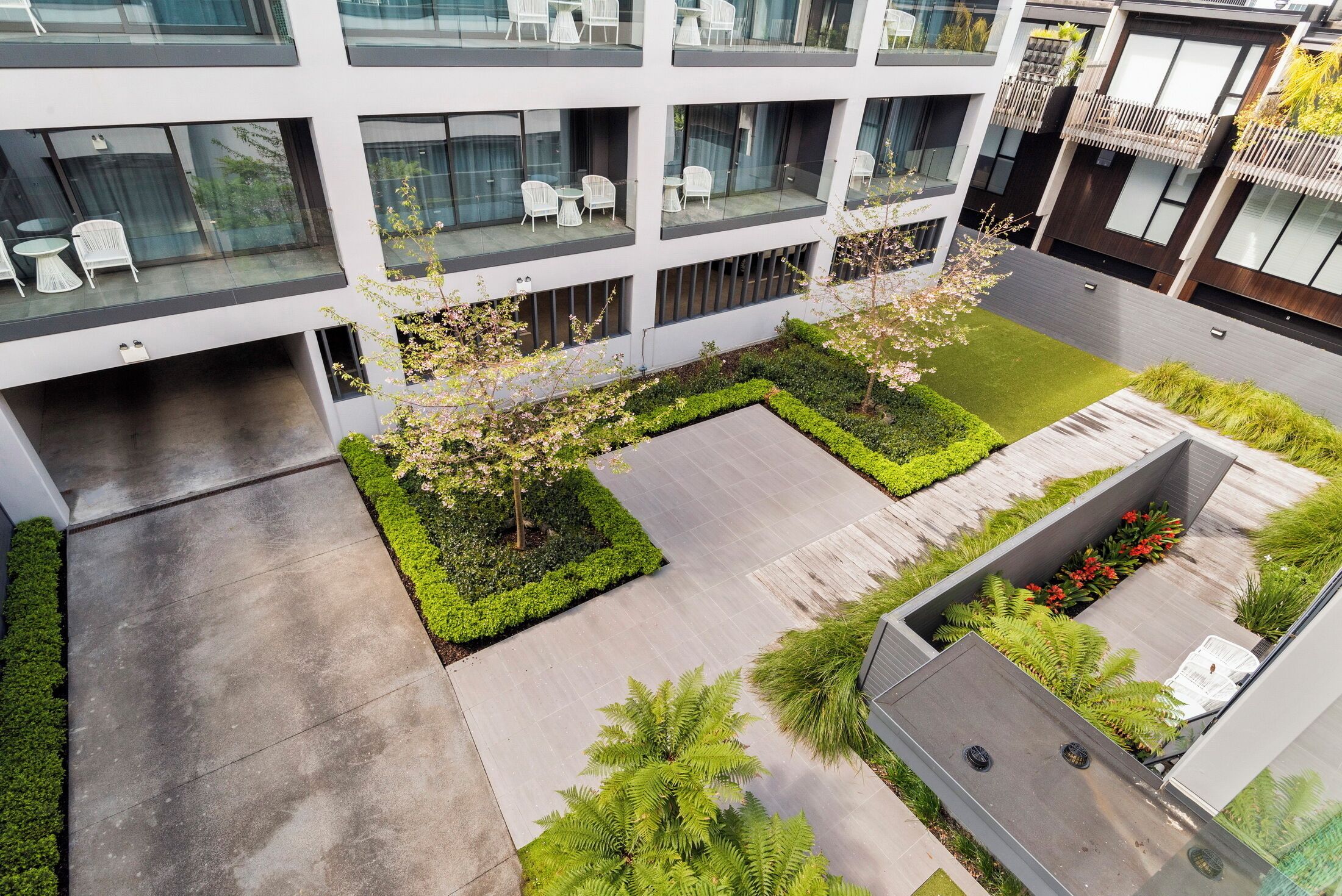 Un edificio moderno con varios balcones, mobiliario exterior y jardines bien cuidados.
