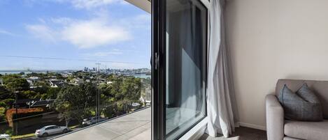 A balcony with a city view, a sofa, and a window with curtains.