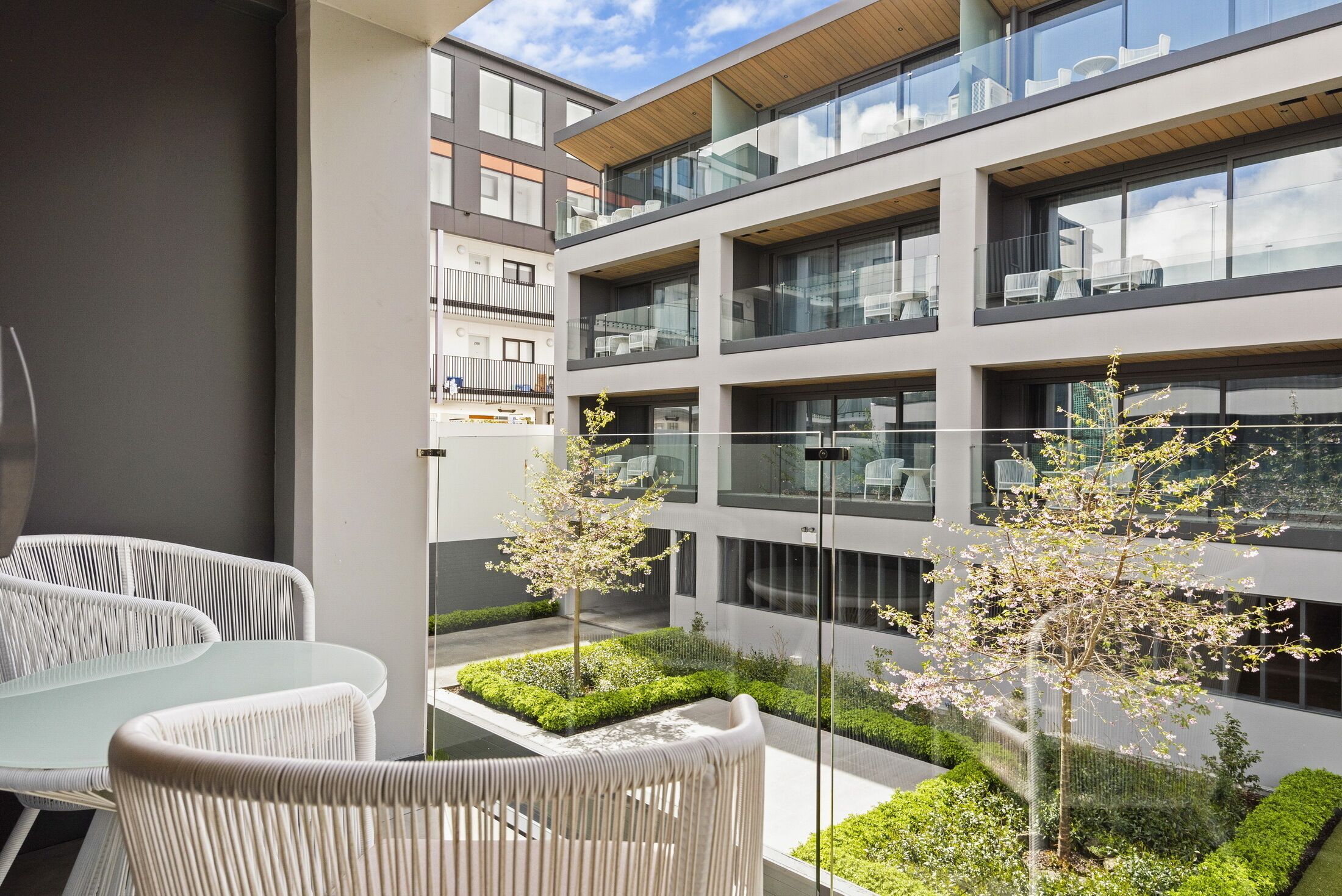 Un edificio moderno con varios balcones, mobiliario exterior y jardines bien cuidados.