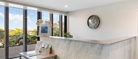 A reception desk with a marble countertop, a clock, and a framed welcome sign.
