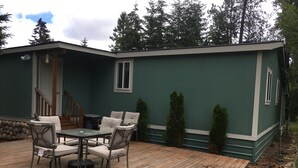 A green house with a wooden deck, outdoor seating, and a staircase leading to the entrance. - Beautiful Cle Elum Getaway- Minutes to Skiing, Hiking, Suncadia (Cle Elum)