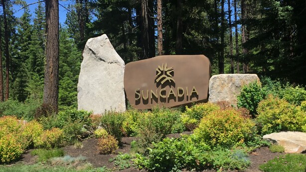 A sign with the word 'SUNCADIA' and a palm tree logo, surrounded by greenery and rocks. - Beautiful Cle Elum Getaway- Minutes to Skiing, Hiking, Suncadia (Cle Elum)