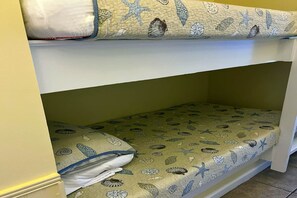 Una cama litera con un colchón en la parte superior y una plaza inferior con almohada.