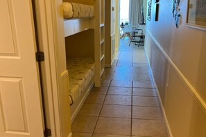 A hallway with bunk beds, a dining area with chairs, and a tiled floor.