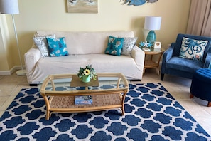 A living room with a sofa, a coffee table, a blue patterned rug, and a lamp. - MILLION DOLLAR VIEW WITH PRIVATE PARKING SLEEPS 6, BOOK 7 DAYS GET 10% DISCOUNT! (Pensacola)