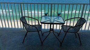 A balcony with two chairs and a table, overlooking the ocean. - MILLION DOLLAR VIEW WITH PRIVATE PARKING SLEEPS 6, BOOK 7 DAYS GET 10% DISCOUNT! (Pensacola)